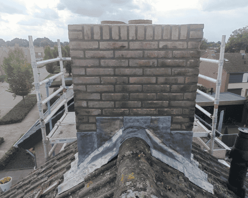 Schoorsteen in steiger tijdens renovatie van voegen en metselwerk.