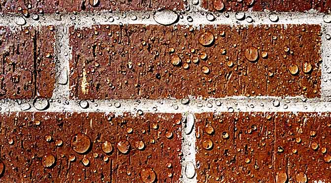 Druppels op een geïmpregneerde rode muur.