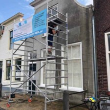 Reiniger staat op een steiger en reinigt een gevel, naast tekst over de kosten van gevelreiniging.